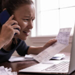 A stressed woman talking on the phone trying to pay her bills. Financial crisis.